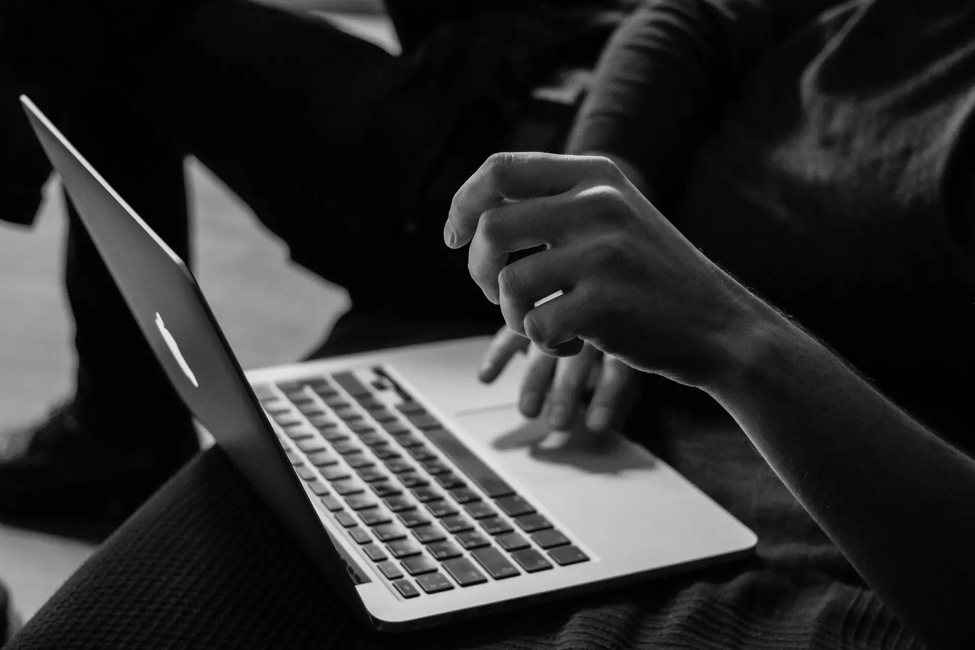 grayscale photo of person using laptop