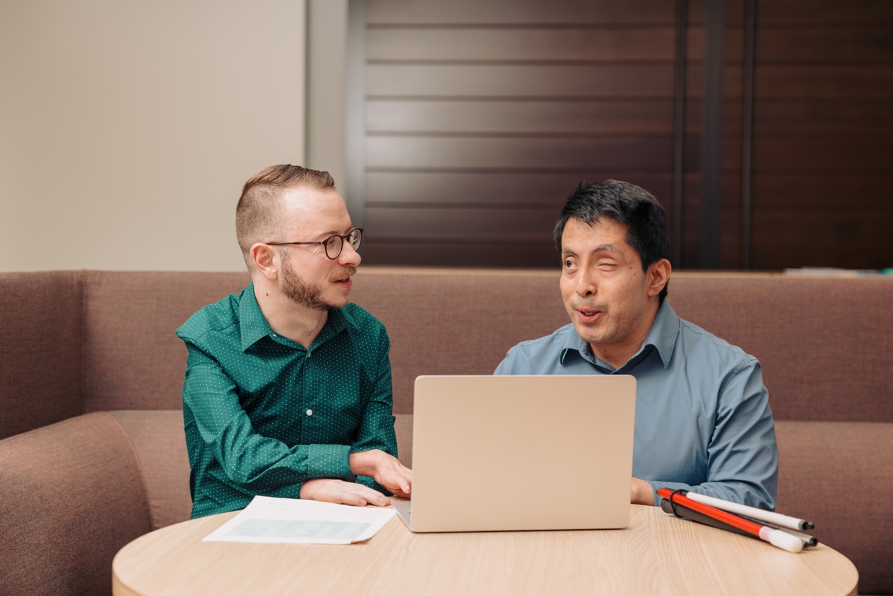 Two colleagues working together at a computer in an accessible workspace